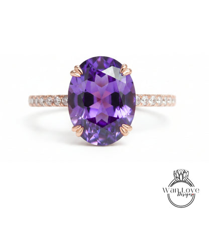 a large oval-shaped purple gemstone, possibly a purple amethyst, set in a ring with a thin gold band and small diamonds.