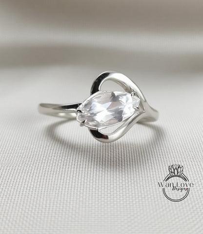 A silver ring with a large, clear gemstone set in a heart-shaped design.