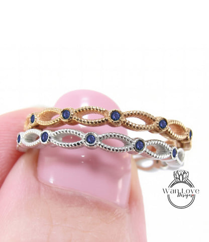 A close-up of a person's hand holding a ring with a row of blue gemstones.