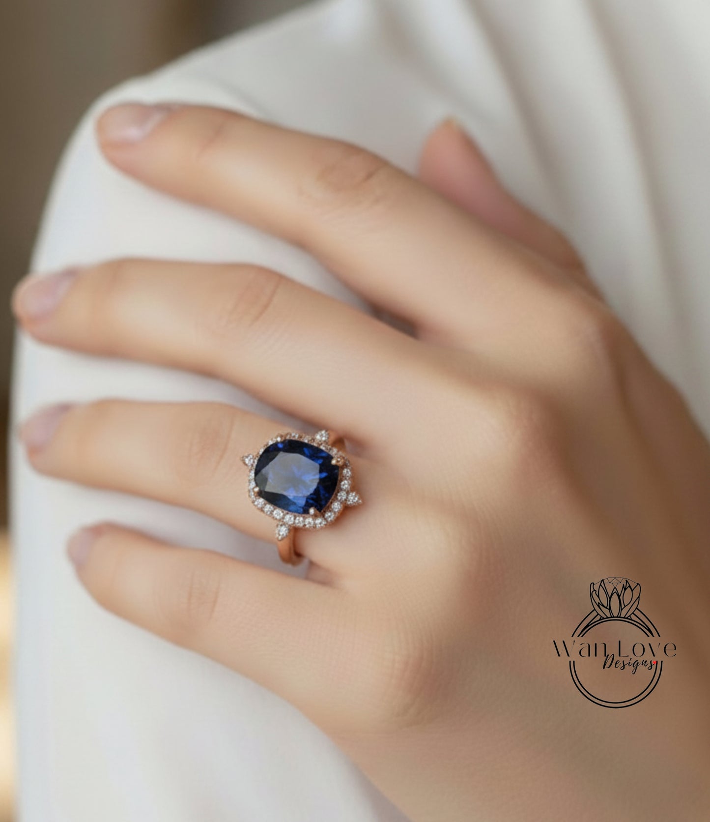 A close-up of a hand wearing a large, blue gemstone ring with a halo of smaller diamonds around it.