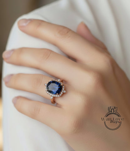 A close-up of a hand wearing a large, blue gemstone ring with a halo of smaller diamonds around it.