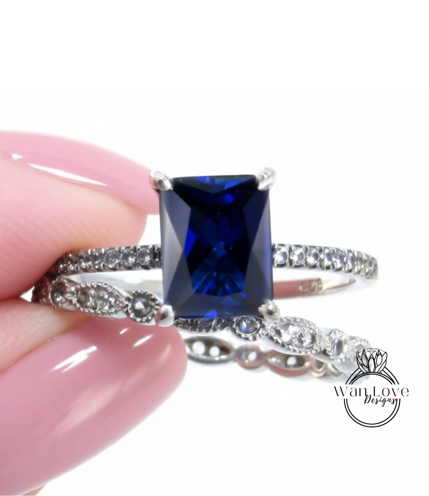 A close-up image of a person's hand holding a ring with a large blue gemstone, likely a sapphire, set in a silver band.