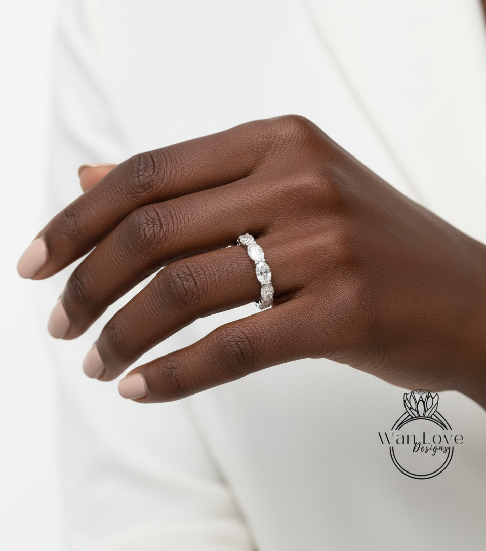 A close-up of a hand wearing a diamond ring on the ring finger.