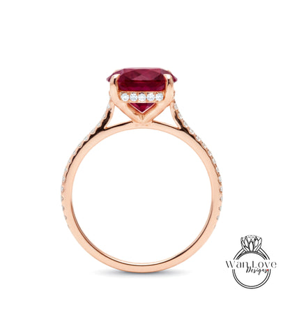 A rose gold engagement ring with a large red gemstone and small diamonds set in the band.