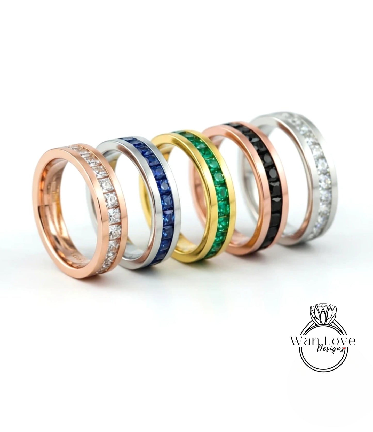 A row of six rings with various gemstones and designs, including diamonds, sapphires, and emeralds, displayed against a white background.