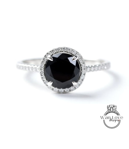 A close-up image of a silver ring with a large black diamond as the centerpiece, surrounded by smaller diamonds.