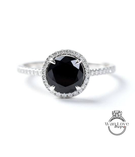 A close-up image of a silver ring with a large black diamond as the centerpiece, surrounded by smaller diamonds.