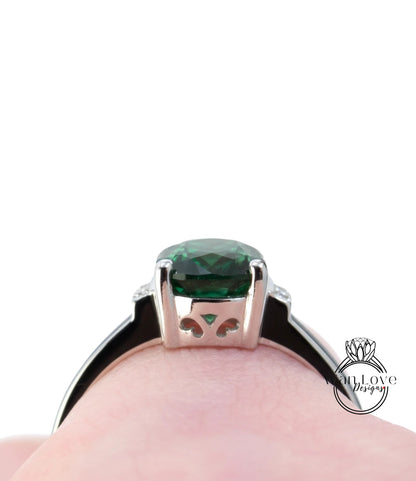 A close-up view of a silver ring with a large green gemstone, showcasing the intricate design and details of the jewelry piece.
