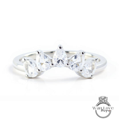 A silver ring with a unique design featuring a row of clear gemstones, including pear-shaped and round-shaped stones, set in a band.