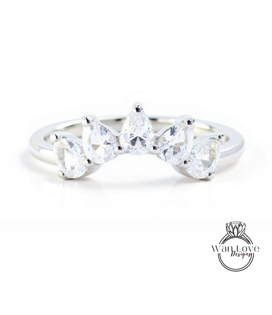 A silver ring with a unique design featuring a row of clear gemstones, including pear-shaped and round-shaped stones, set in a band.