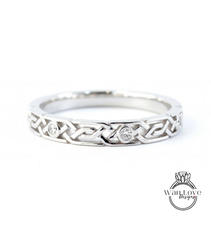 A silver ring with a Celtic knot design and two diamonds set in the center.