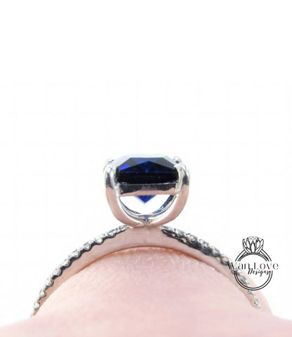 A close-up view of a silver ring with a large blue gemstone, possibly a sapphire, set in a halo of smaller diamonds.