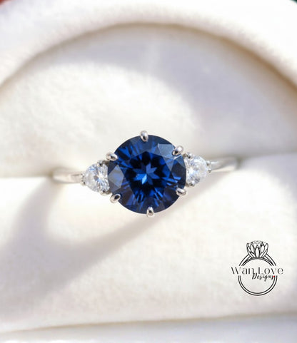 A close-up image of a silver ring with a large blue gemstone, possibly a sapphire, surrounded by smaller diamonds.