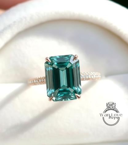 A close-up image of a gold ring with a large, rectangular emerald gemstone set in the center.