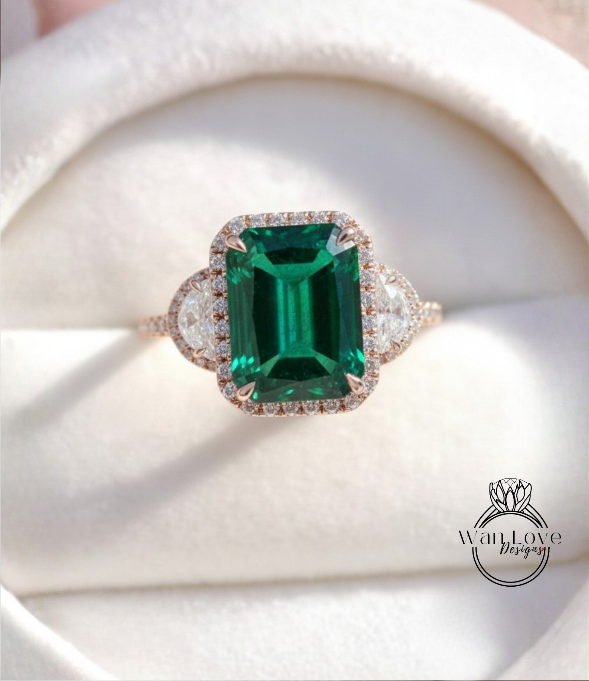 A close-up of a beautiful green gemstone ring with a halo of diamonds around it, displayed in a white box.