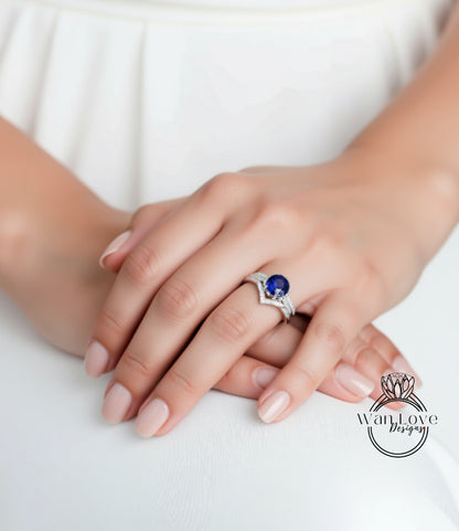 A close-up of a person's hand wearing a ring with a blue gemstone, resting on a white surface.
