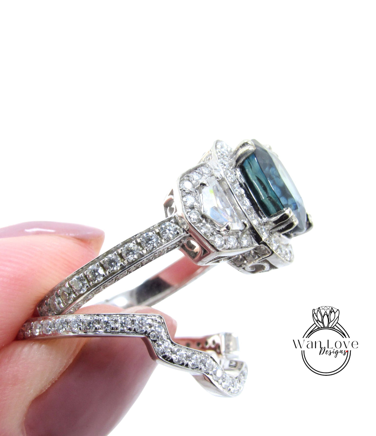 A close-up image of a person's hand holding a diamond engagement ring with a large blue gemstone.