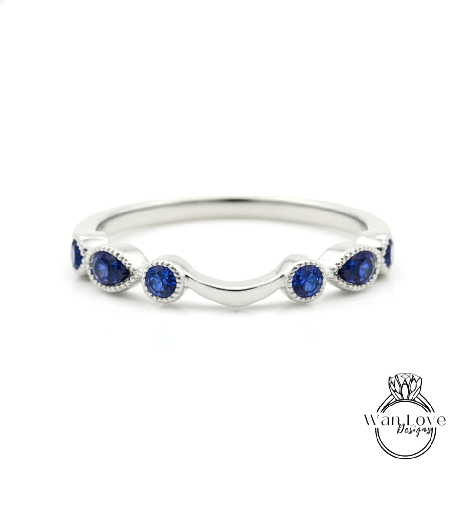 A silver ring with a curved band and blue sapphire stones.