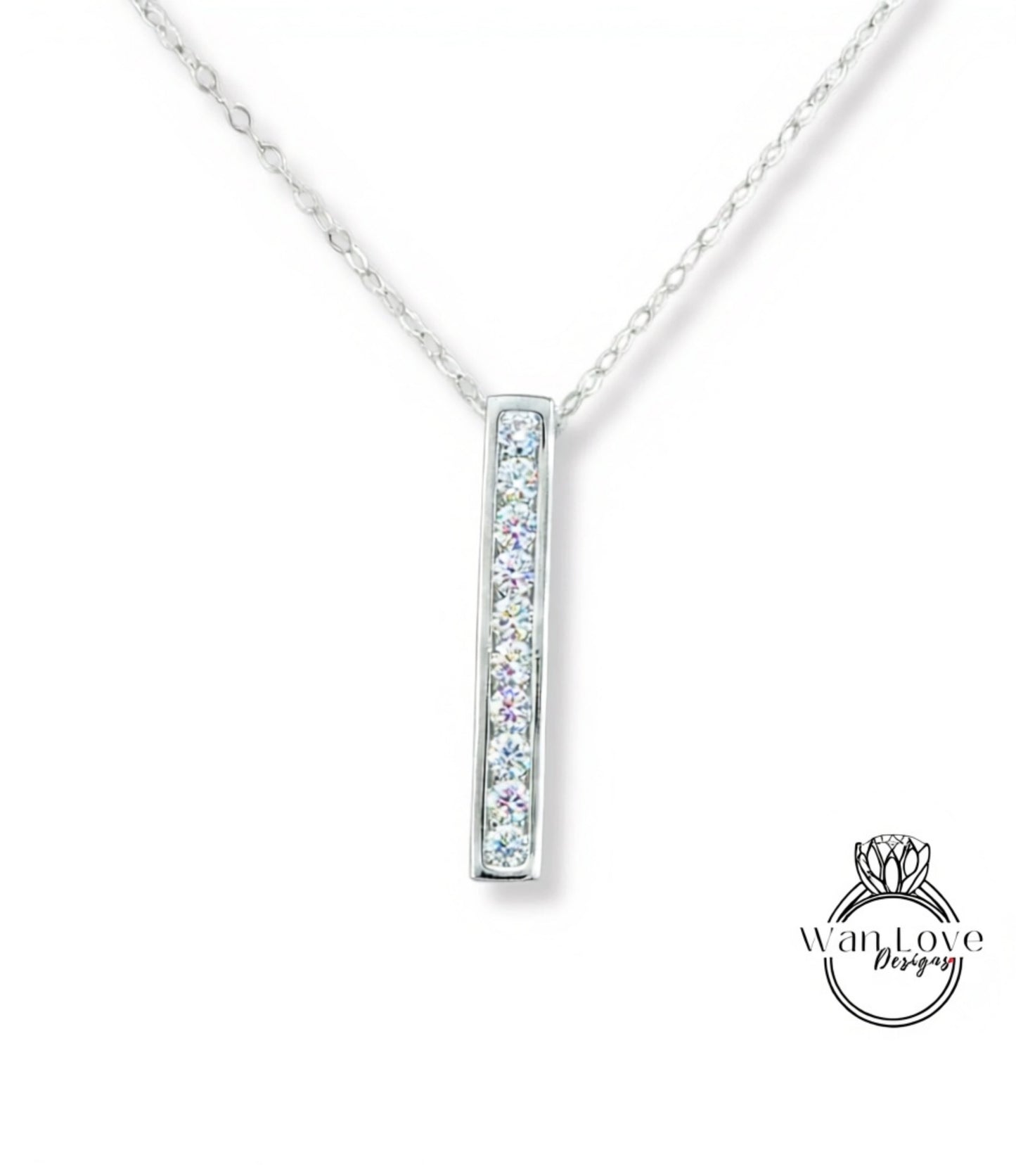 A silver necklace with a rectangular pendant featuring a row of clear gemstones.