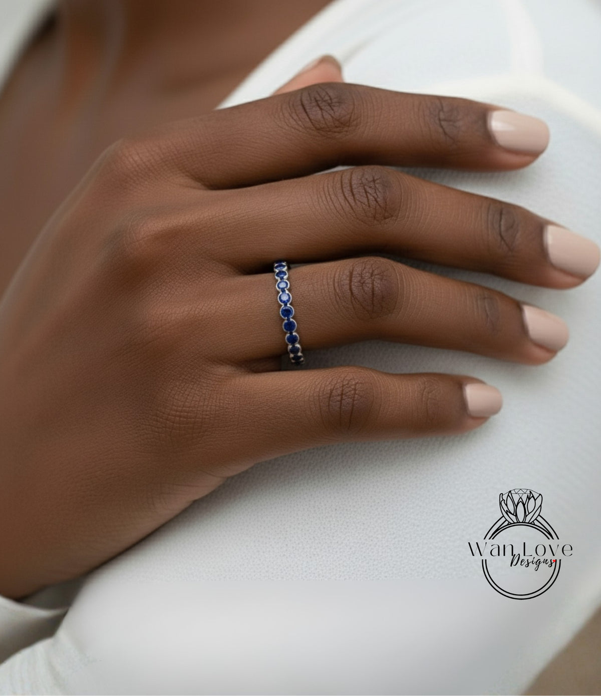A close-up of a person's hand wearing a ring with blue stones.