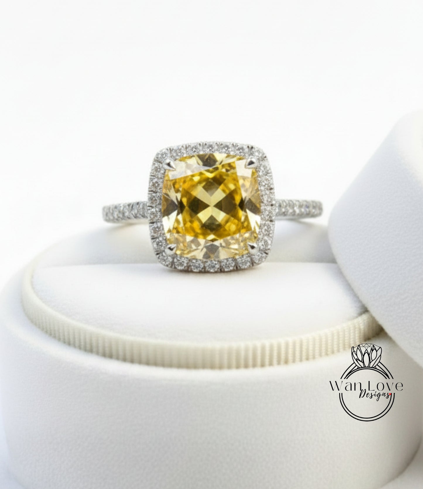 A yellow diamond ring with a halo of smaller diamonds around the center stone, displayed on a white velvet background.