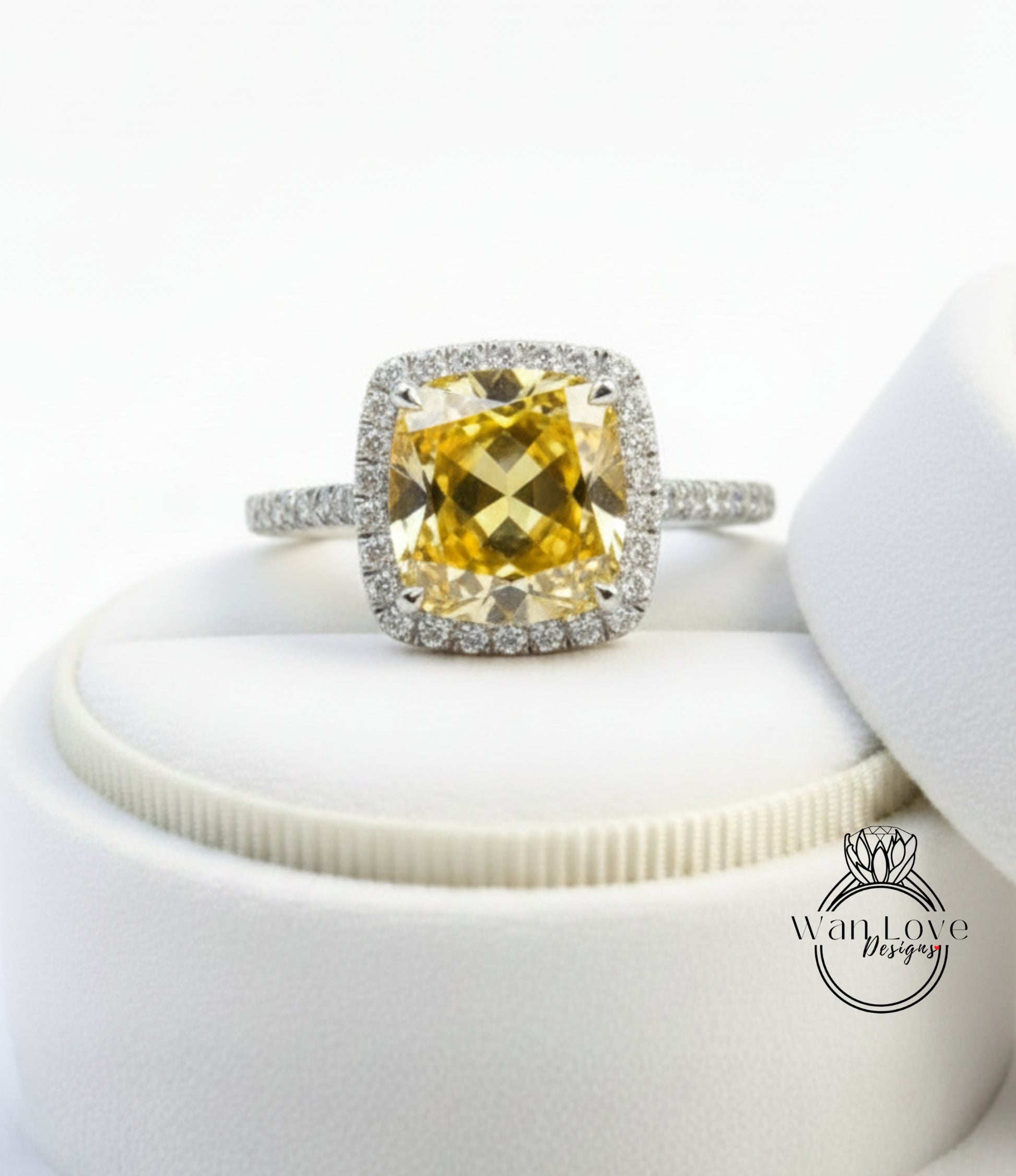 A yellow diamond ring with a halo of smaller diamonds around the center stone, displayed on a white velvet background.