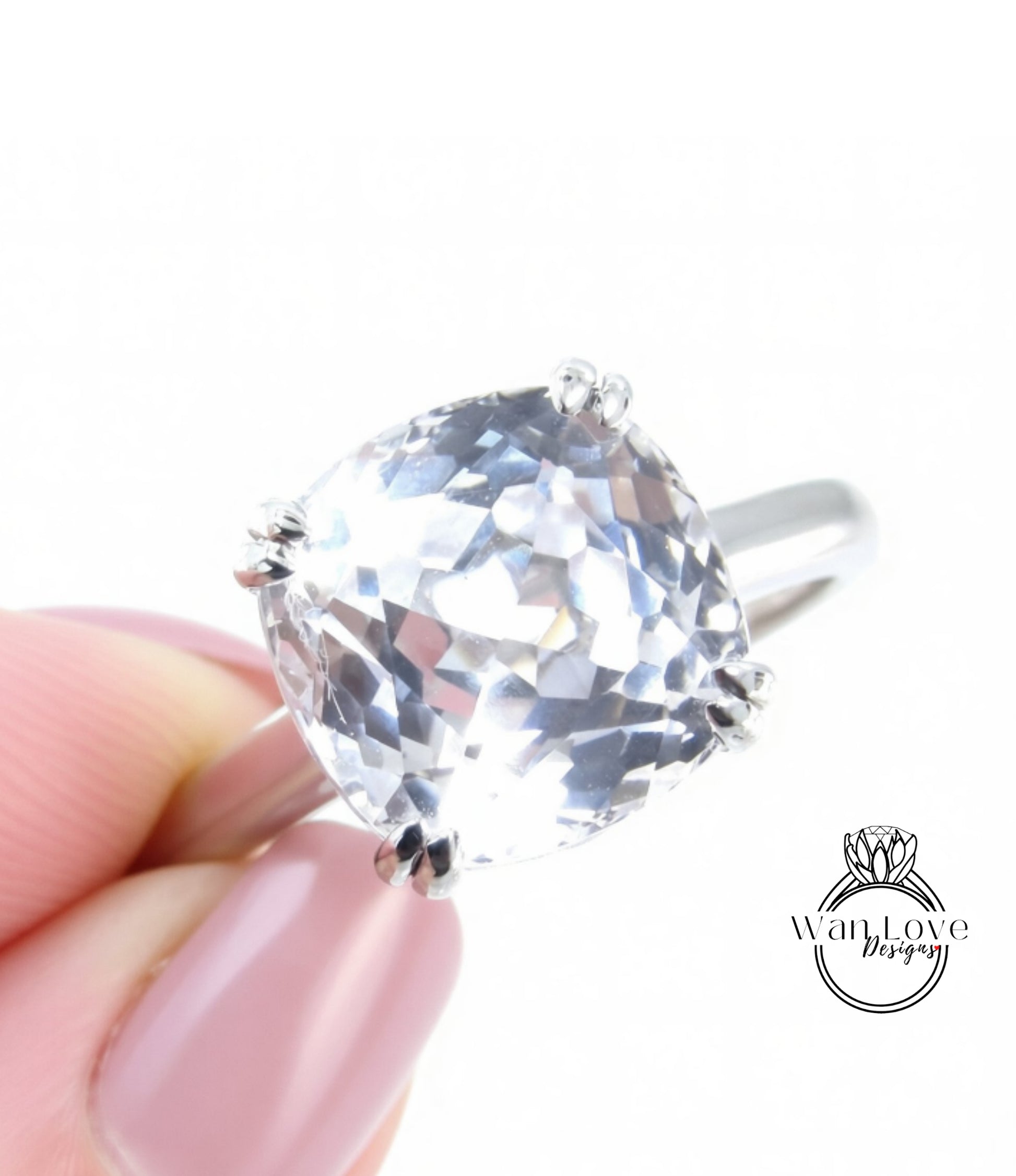 A close-up image of a person's hand holding a large, clear gemstone ring.