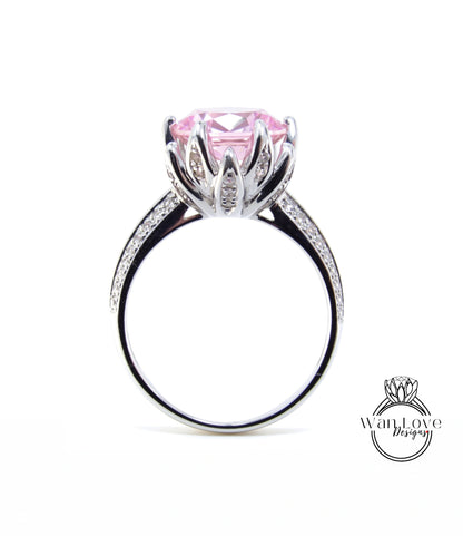 A silver ring with a large pink gemstone, likely a diamond, set in a decorative flower-like design.