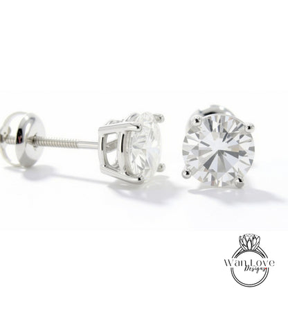 A pair of elegant silver earrings with a large, clear diamond set in the center, resting on a white background.