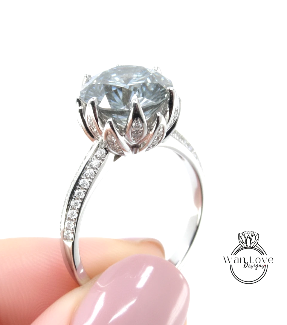 A close-up of a person's hand holding a silver ring with a large, clear gemstone, likely a diamond, on the ring.