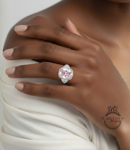 A close-up of a person's hand wearing a large, pink diamond ring on the ring finger.