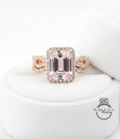 A pink gemstone engagement ring with a halo of diamonds set in a gold band, displayed on a white cloth.