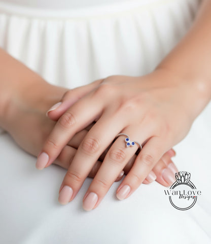 A close-up image of a person's hands wearing a ring with blue gemstones.