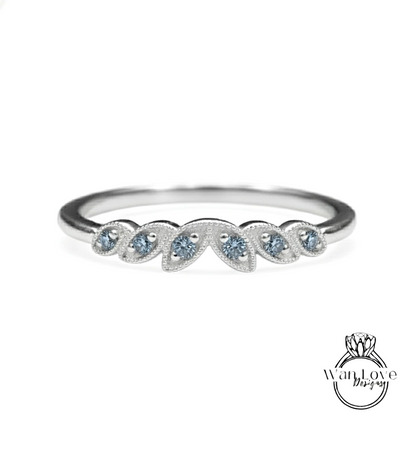 A silver ring with a row of blue gemstones on the band.