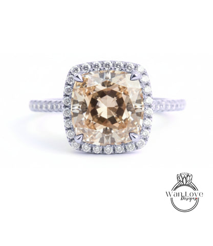 A large, round, beige diamond set in a halo of smaller diamonds, surrounded by a halo of smaller diamonds on a silver ring.