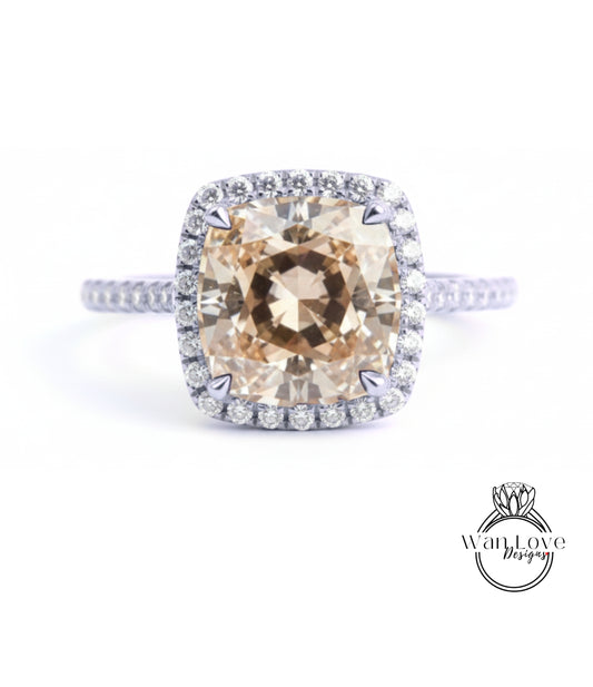 A large, round, beige diamond set in a halo of smaller diamonds, surrounded by a halo of smaller diamonds on a silver ring.