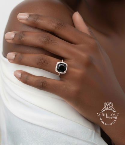 A close-up of a person's hand wearing a ring with a large black gemstone, likely a diamond, set in a gold ring band.