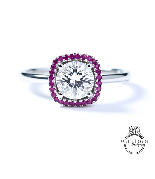 A diamond engagement ring with a large central diamond surrounded by a halo of smaller diamonds and a border of red gemstones.