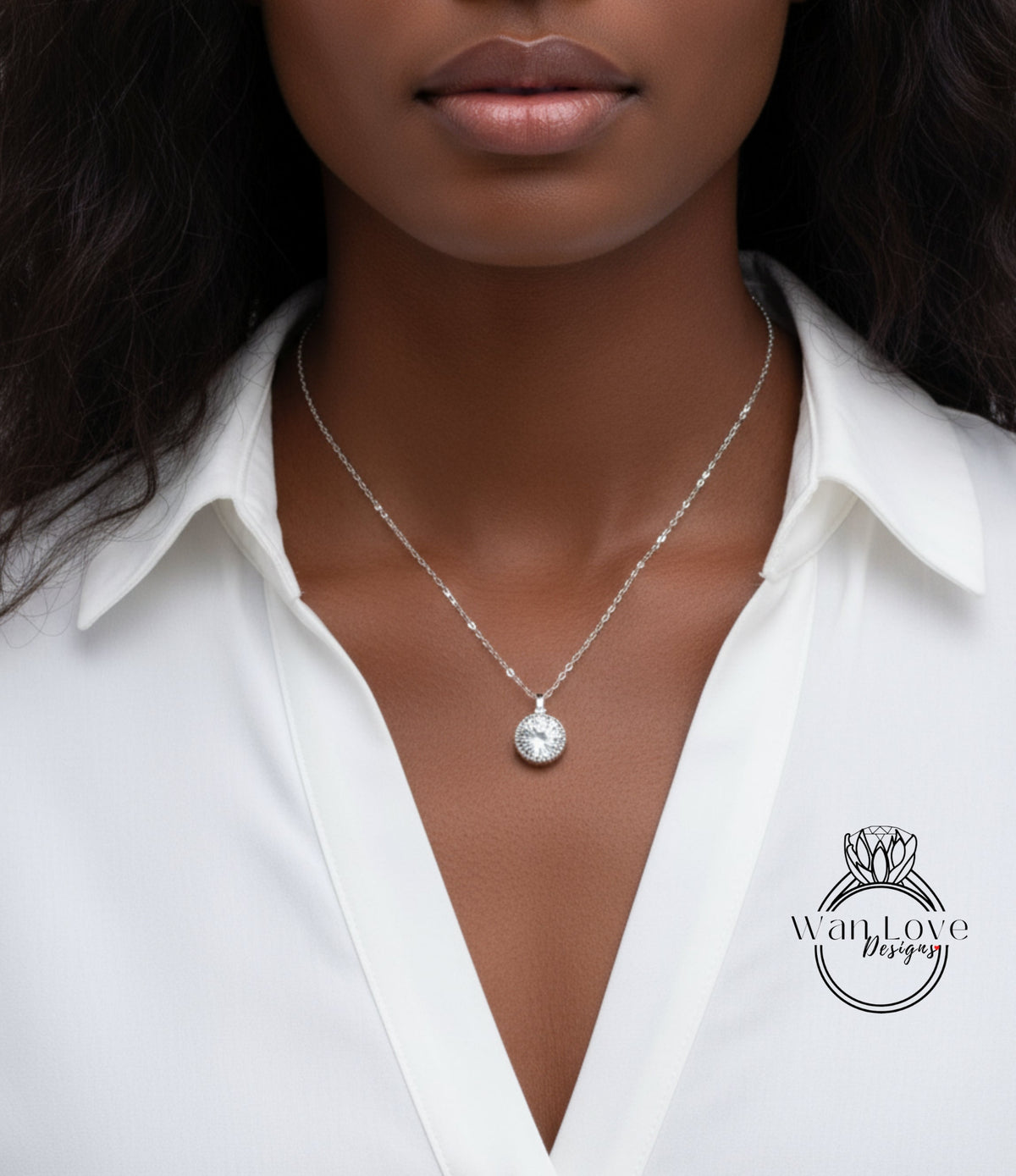 A close-up of a woman wearing a white blouse and a necklace with a pendant.
