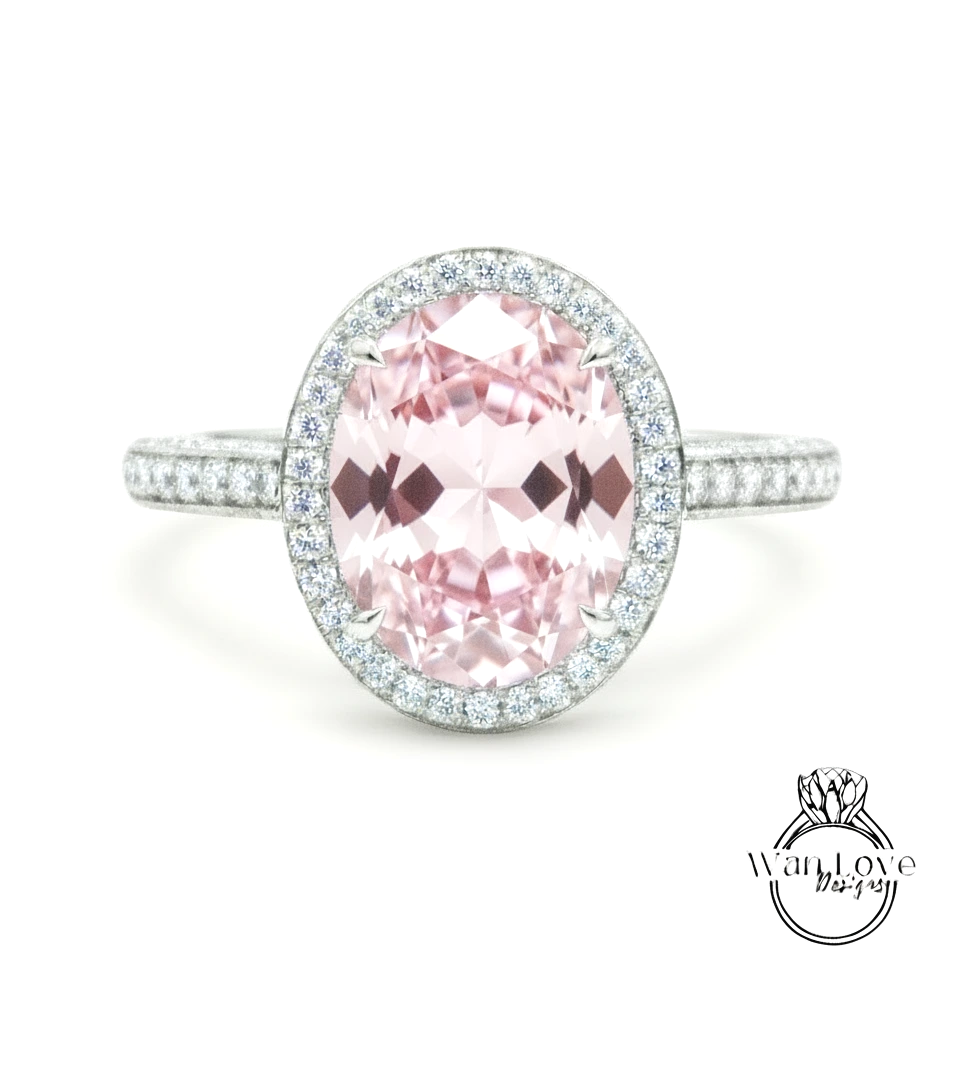 A beautiful pink gemstone ring with a halo of smaller diamonds around the center stone.