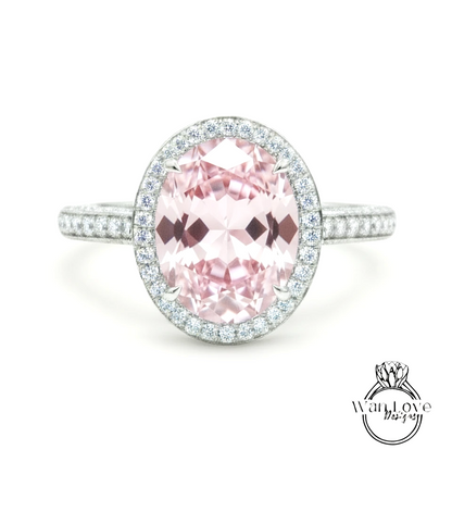A beautiful pink gemstone ring with a halo of smaller diamonds around the center stone.