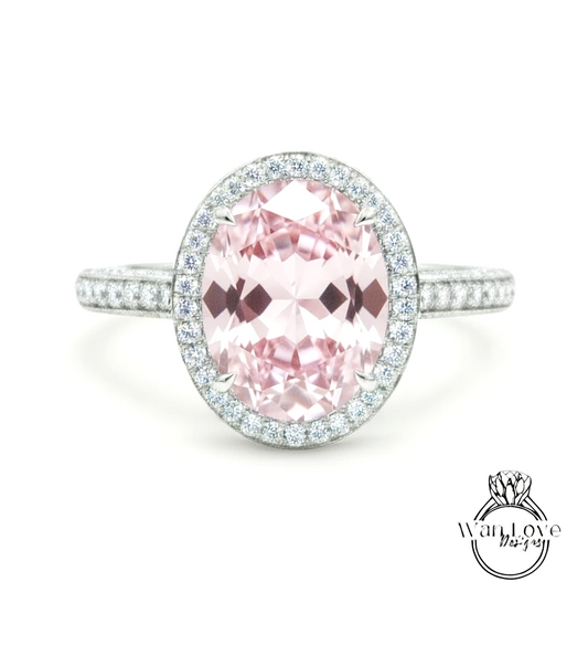 A beautiful pink gemstone ring with a halo of smaller diamonds around the center stone.