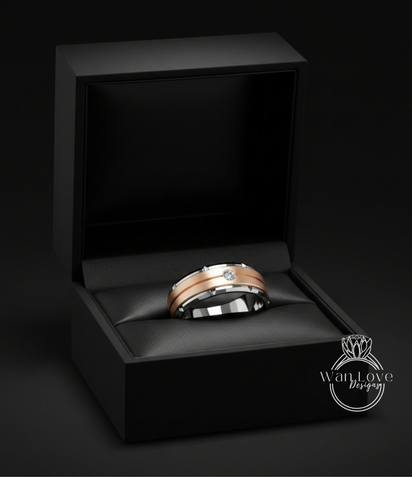 A gold and silver wedding ring is displayed in a black jewelry box against a dark background.