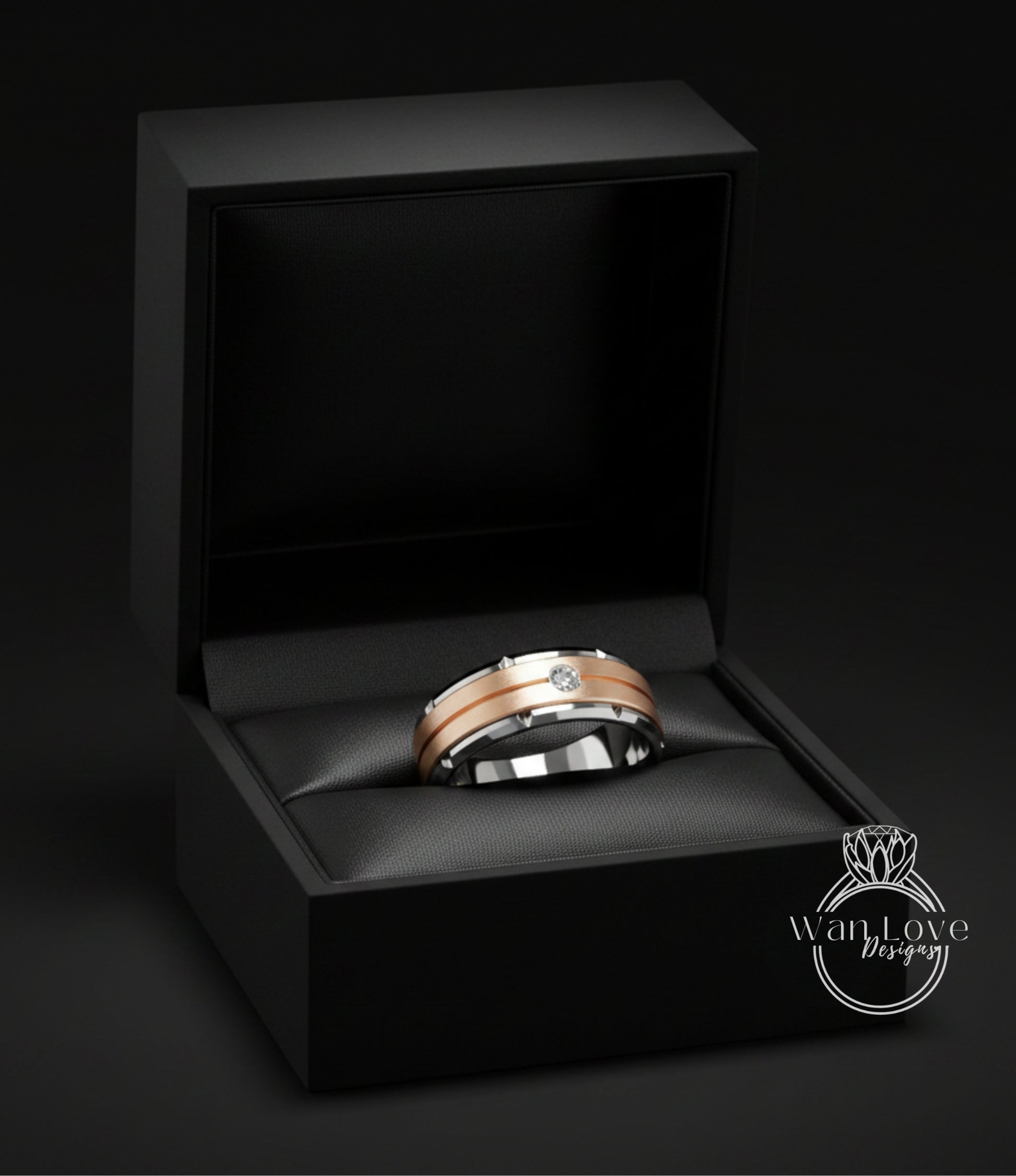 A gold and silver wedding ring is displayed in a black jewelry box against a dark background.