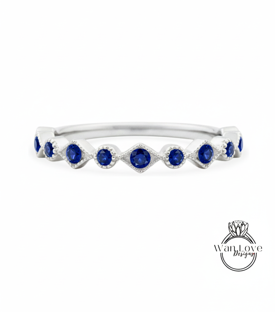 A silver ring with a row of blue sapphire stones set in a diamond pattern.