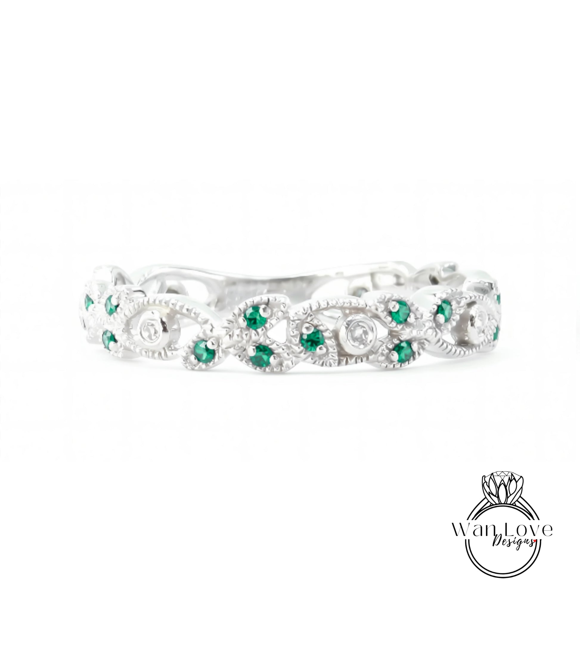 A silver ring with a decorative band adorned with green gemstones.