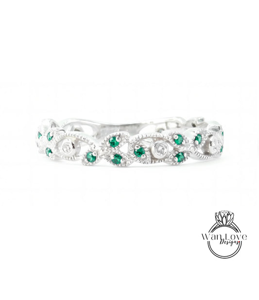 A silver ring with a decorative band adorned with green gemstones.