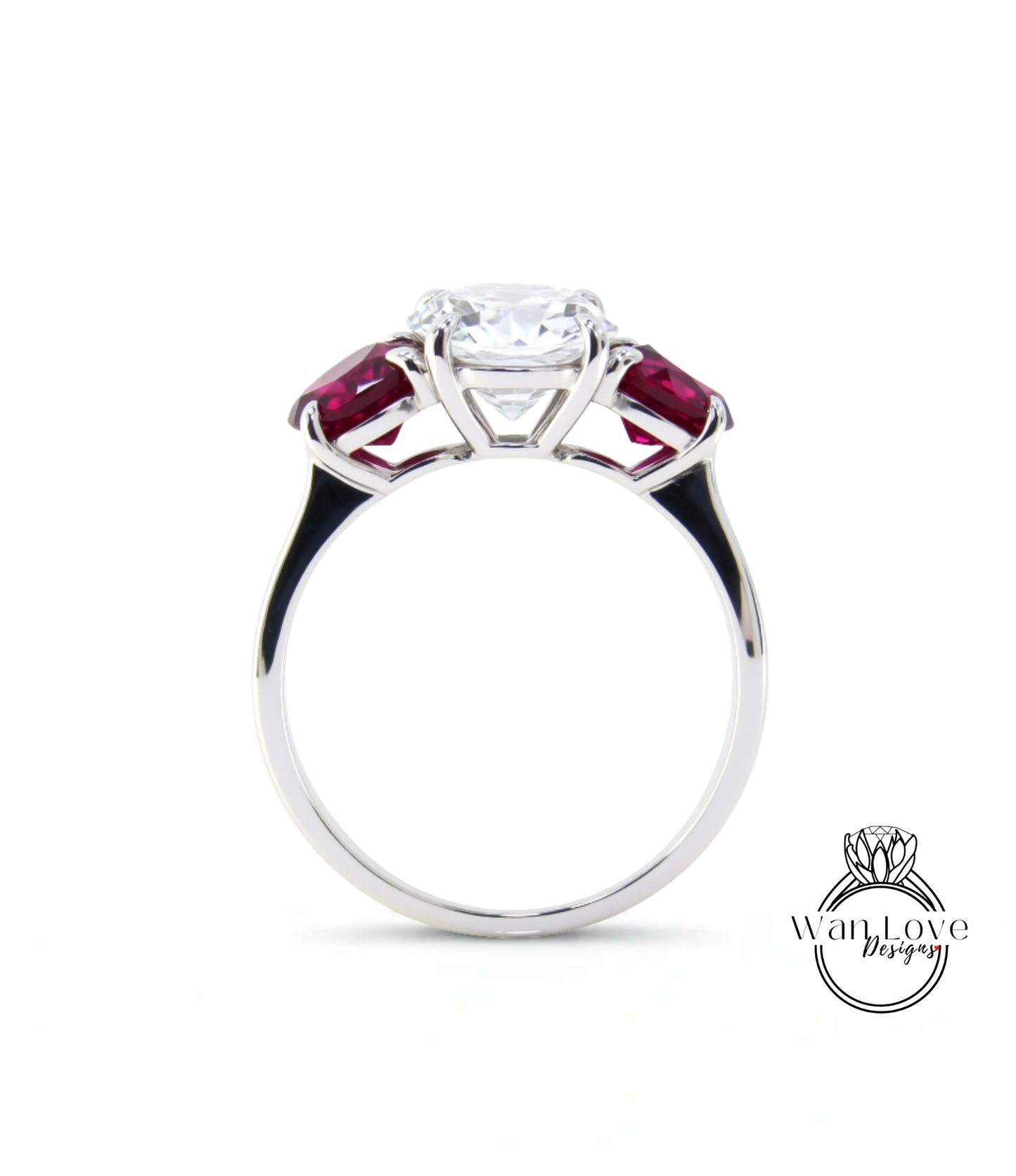 A silver engagement ring with a large central diamond surrounded by two smaller diamonds on either side, set in a silver band with a red gemstone.
