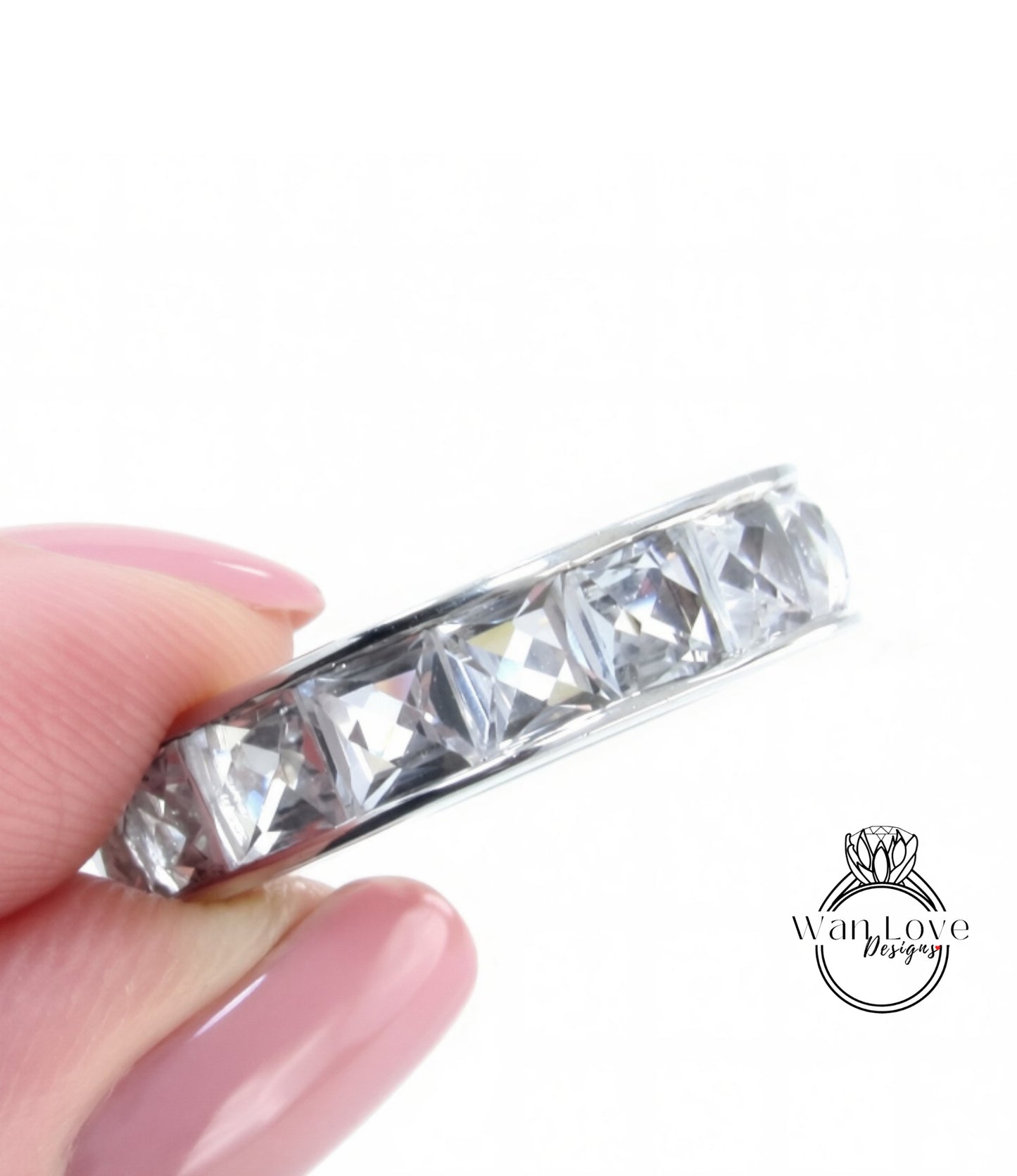 A close-up image of a person's hand holding a ring with a row of clear gemstones.