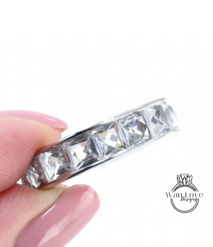A close-up image of a person's hand holding a ring with a row of clear gemstones.
